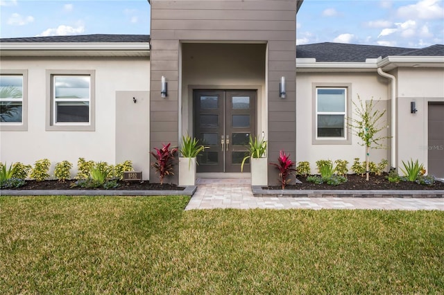 view of exterior entry with a lawn and french doors