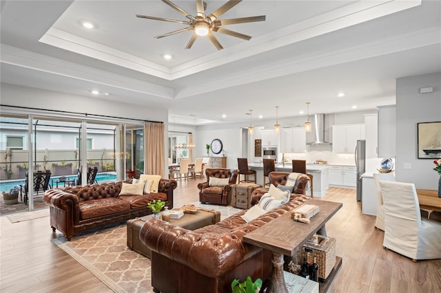 living room featuring sink, a raised ceiling, and light hardwood / wood-style floors