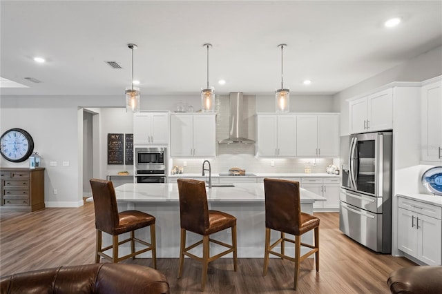 kitchen with wall chimney exhaust hood, stainless steel appliances, hanging light fixtures, and white cabinets