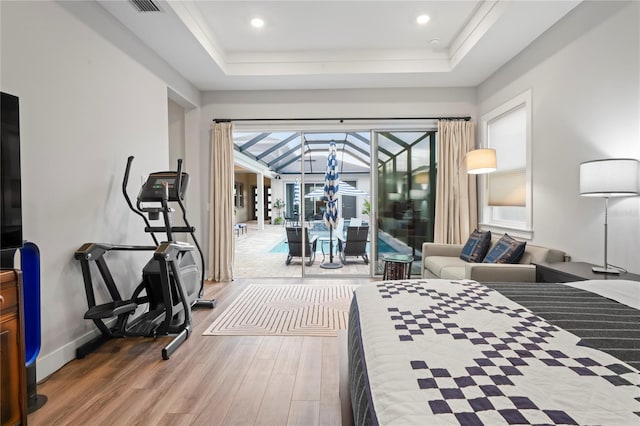 bedroom featuring a tray ceiling, access to outside, and wood-type flooring