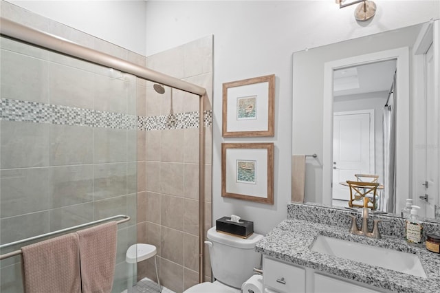 bathroom featuring vanity, a shower with door, and toilet