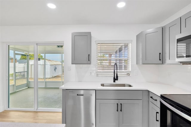 kitchen with decorative backsplash, sink, gray cabinets, and stainless steel appliances