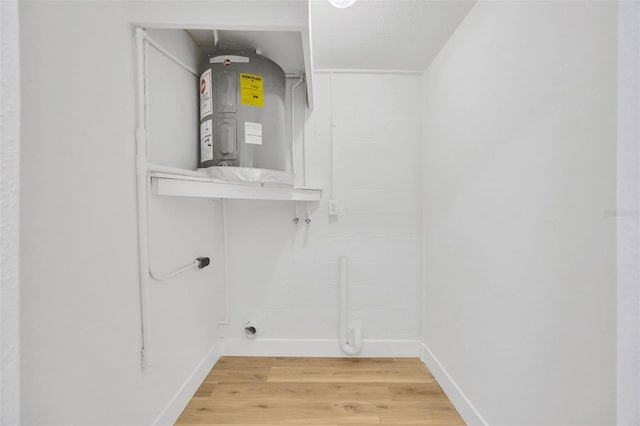 interior space featuring water heater, hardwood / wood-style flooring, and hookup for an electric dryer