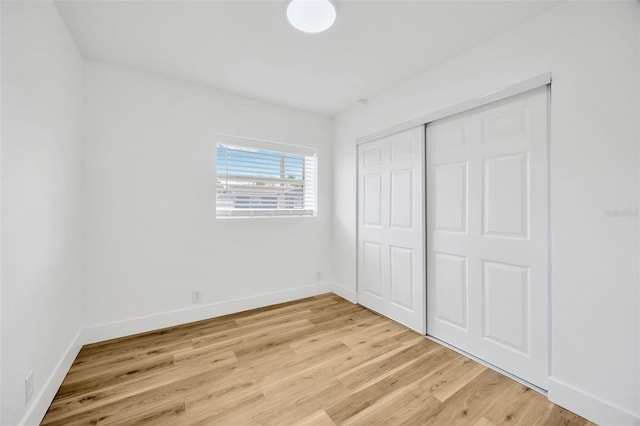 unfurnished bedroom with a closet and light hardwood / wood-style floors