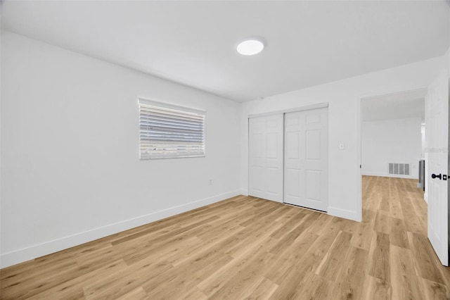 unfurnished bedroom with a closet and light hardwood / wood-style floors