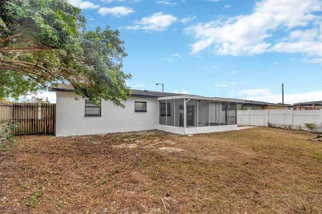 rear view of property featuring a sunroom and a lawn