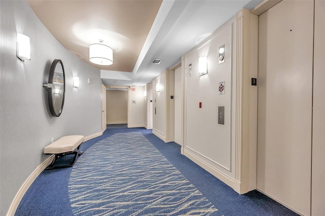 hallway with dark carpet and elevator