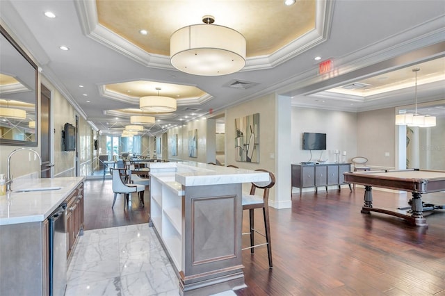 kitchen with a raised ceiling, sink, crown molding, billiards, and decorative light fixtures