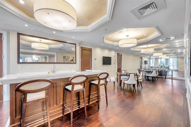 interior space featuring a tray ceiling, sink, dark wood-type flooring, and ornamental molding