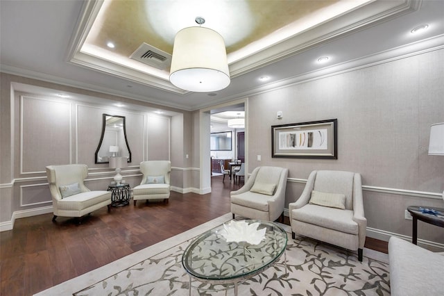 sitting room featuring dark hardwood / wood-style floors, a raised ceiling, and ornamental molding