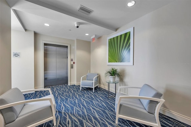 living area with elevator and dark carpet