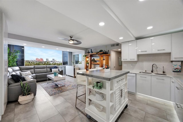 kitchen featuring white cabinetry, decorative backsplash, a kitchen island, and sink