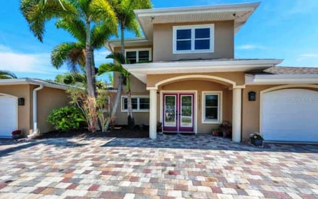 view of front of property featuring stucco siding, french doors, and decorative driveway