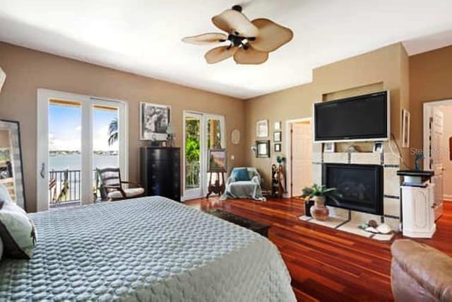 bedroom with hardwood / wood-style flooring, ceiling fan, access to exterior, and a water view