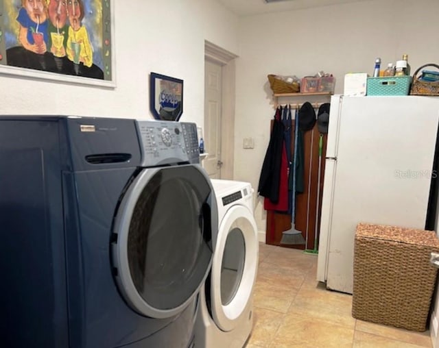 clothes washing area with washing machine and dryer and light tile patterned floors