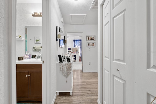 hall featuring hardwood / wood-style floors, sink, and a textured ceiling