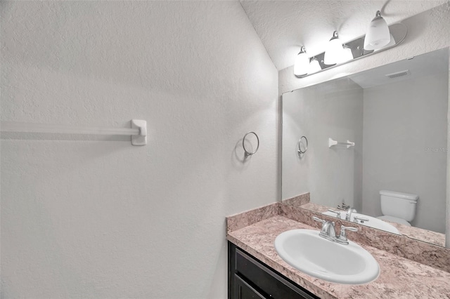 bathroom with vanity, a textured ceiling, and toilet