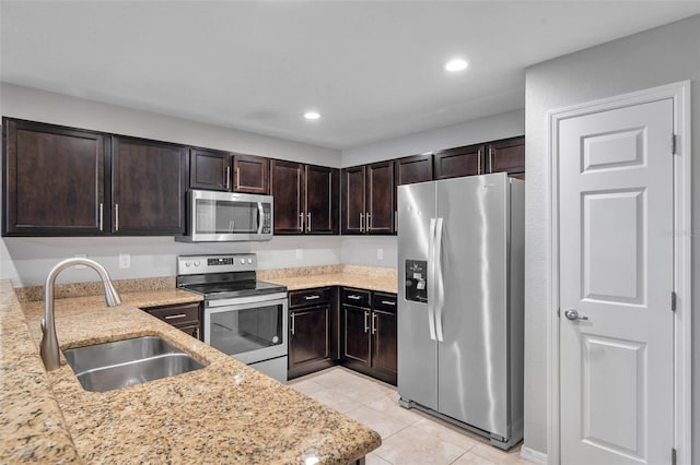 kitchen featuring light tile patterned flooring, dark brown cabinetry, sink, appliances with stainless steel finishes, and light stone countertops