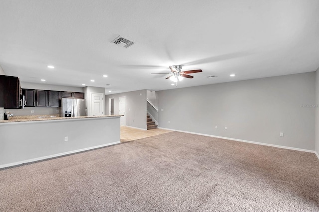 unfurnished living room featuring light carpet and ceiling fan