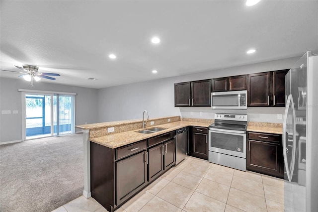 kitchen with sink, stainless steel appliances, dark brown cabinetry, light carpet, and kitchen peninsula