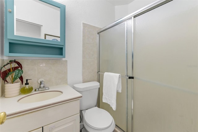 bathroom featuring tasteful backsplash, vanity, a shower with door, and toilet