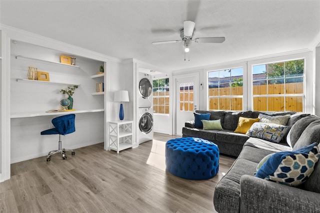 interior space with hardwood / wood-style flooring, ornamental molding, ceiling fan, and stacked washer / dryer