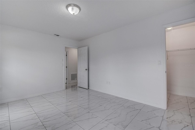 unfurnished bedroom featuring a walk in closet, a closet, and a textured ceiling