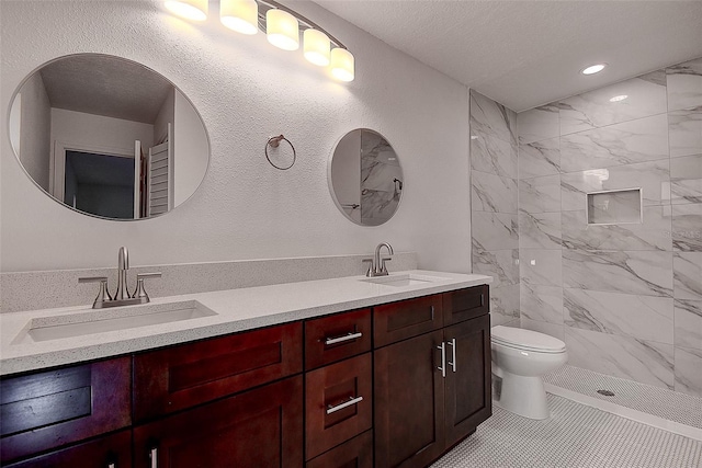 bathroom with tile patterned flooring, tiled shower, vanity, a textured ceiling, and toilet