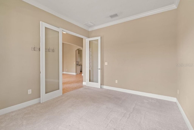 spare room with french doors, crown molding, and light carpet