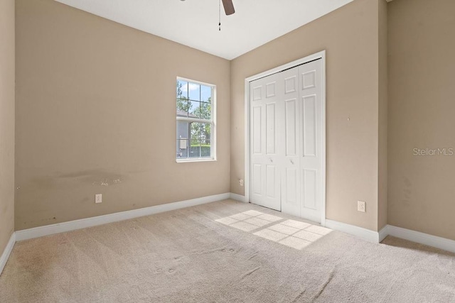 unfurnished bedroom with light carpet, a closet, and ceiling fan