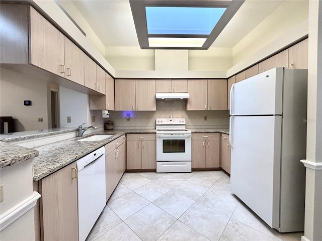 kitchen featuring sink, white appliances, a skylight, light brown cabinetry, and light stone counters