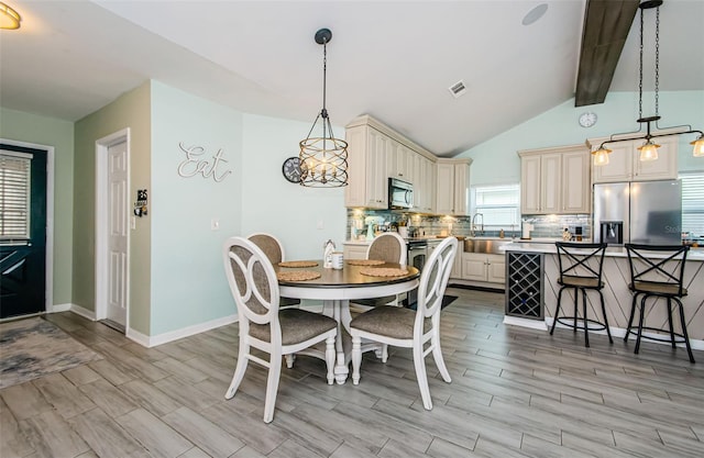 dining space with vaulted ceiling with beams and sink