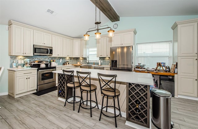 kitchen with light wood-type flooring, stainless steel appliances, lofted ceiling with beams, and decorative light fixtures