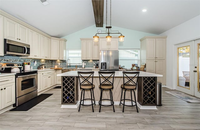 kitchen with vaulted ceiling with beams, pendant lighting, stainless steel appliances, and a center island