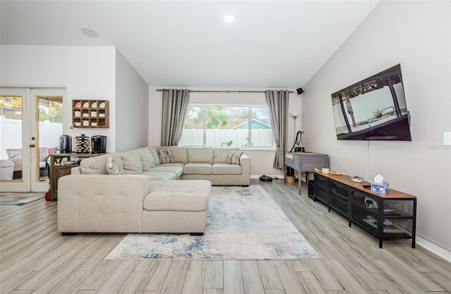 living room with vaulted ceiling, plenty of natural light, light hardwood / wood-style floors, and french doors