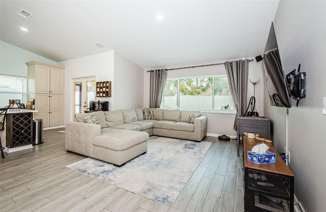 living room featuring lofted ceiling, a healthy amount of sunlight, and light hardwood / wood-style flooring