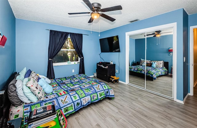 bedroom with hardwood / wood-style floors, a closet, a textured ceiling, and ceiling fan