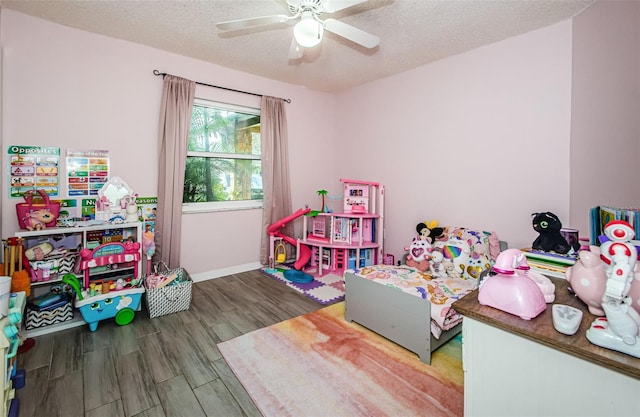 game room featuring ceiling fan, wood-type flooring, and a textured ceiling