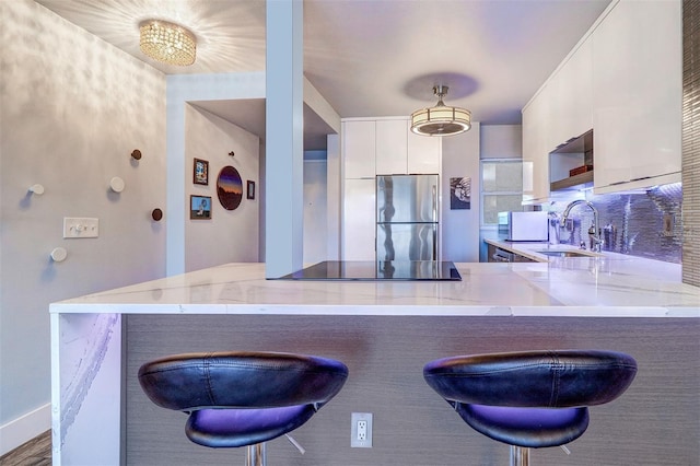 kitchen with sink, stainless steel fridge, a breakfast bar, and kitchen peninsula