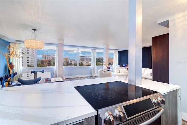 kitchen with stainless steel range with electric stovetop, hardwood / wood-style floors, pendant lighting, and light stone counters