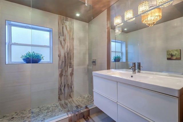 bathroom with an inviting chandelier, tile patterned floors, vanity, and a tile shower