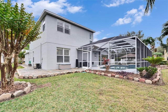 rear view of property featuring glass enclosure, a patio area, and a lawn