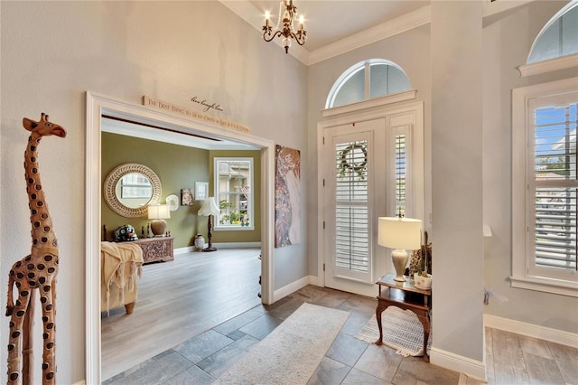 entrance foyer featuring a healthy amount of sunlight, crown molding, light hardwood / wood-style floors, and a notable chandelier