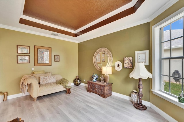 living area with light hardwood / wood-style floors, a tray ceiling, and ornamental molding