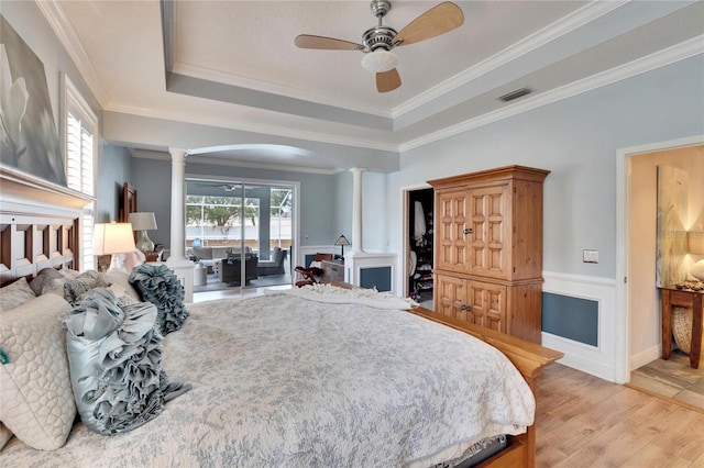 bedroom with ceiling fan, access to exterior, ornamental molding, a raised ceiling, and decorative columns