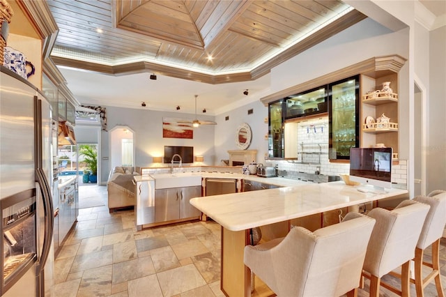 kitchen featuring kitchen peninsula, a kitchen bar, crown molding, stainless steel appliances, and wooden ceiling