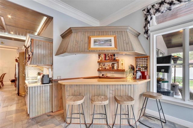 kitchen with kitchen peninsula, backsplash, a breakfast bar area, and ornamental molding