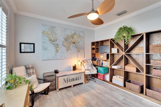 sitting room with ceiling fan, ornamental molding, and light wood-type flooring