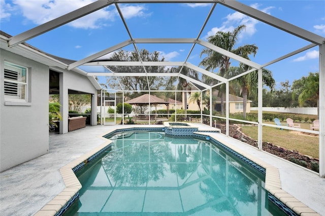 view of pool featuring glass enclosure, an in ground hot tub, and a patio