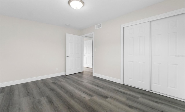 unfurnished bedroom with dark wood-type flooring and a closet